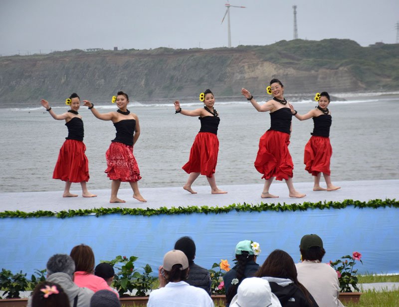 屏風ケ浦を背にして笑顔でフラを披露するダンサー＝２０日、銚子市
