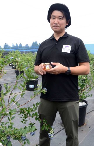 ブルーベリーの花から採取された蜂蜜を持つ宇井代表＝東金市