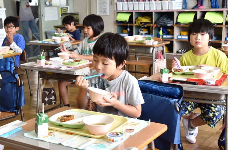 館山市産のご飯を頬張る１年生児童＝１４日、同市