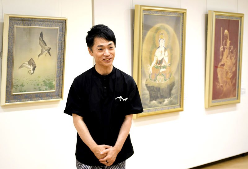 父親の小幡春生氏が描いた絵の魅力を説明する龍生さん＝成田市