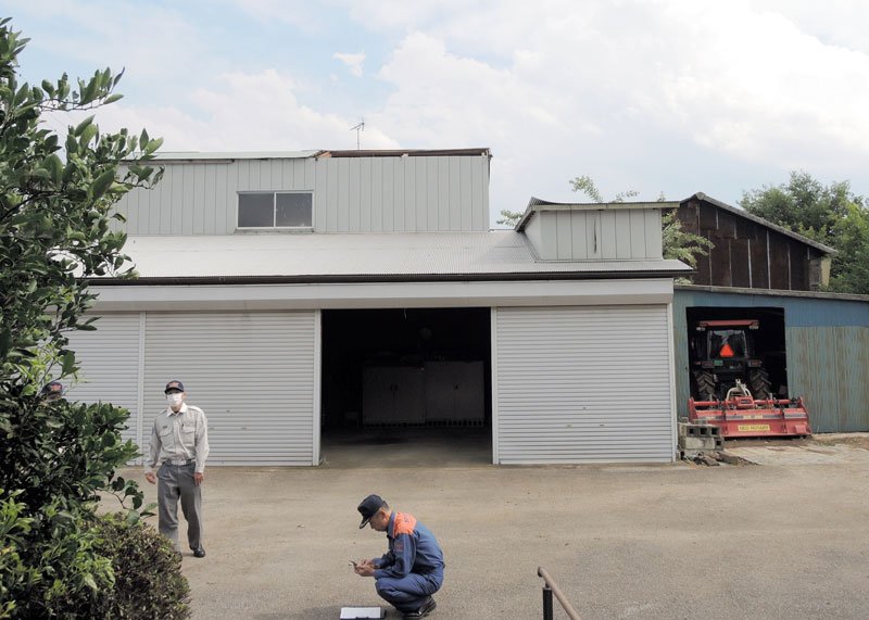 トタン屋根が飛ばされるなどの被害に遭った敷地内で調査に当たる野田市消防本部の職員ら＝１２日、野田市
