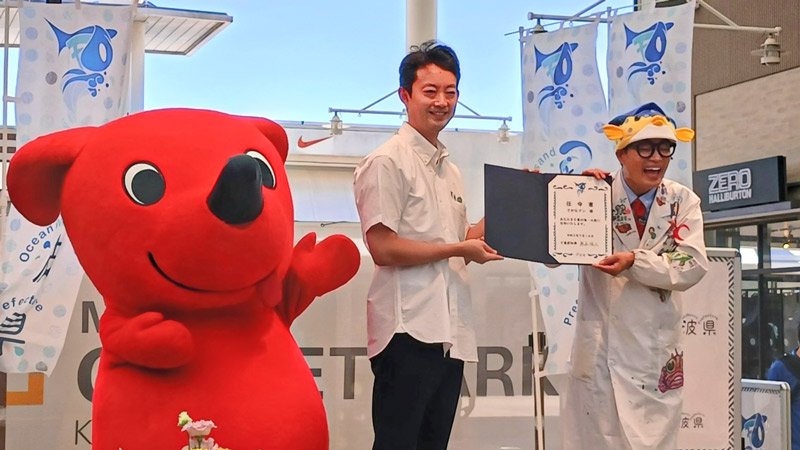 熊谷知事（中央）から任命書を贈られたさかなクン＝１６日、木更津市の三井アウトレットパーク木更津