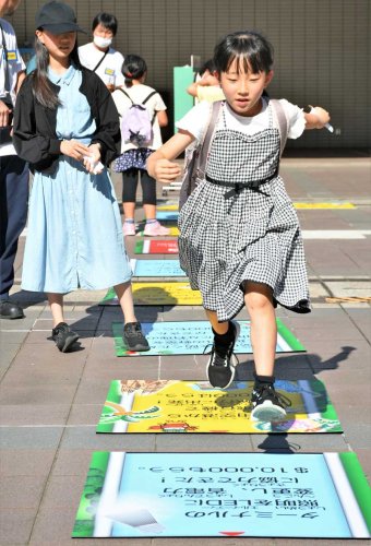 成田空港の魅力やＳＤＧｓの取り組みが書かれたリアル人生ゲームのマス目を勢い良く進む小学生＝２９日午後、成田市