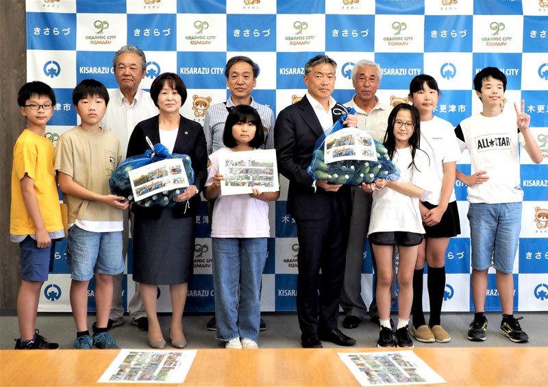育てたトウモロコシと栽培体験記録を披露した６年生代表ら＝木更津市
