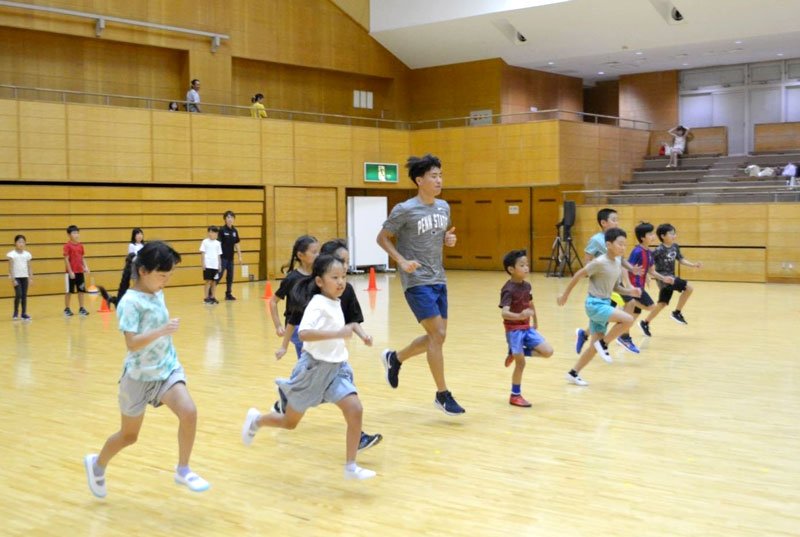 夏休みＲＵＮラン教室で石井選手（中央）と一緒に走る児童＝市原市のゼットエー武道場（市原市スポーツ協会提供）