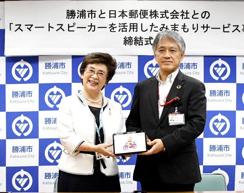 見守り事業で連携する勝浦市の照川由美子市長（左）と日本郵便の茂木孝之関東支社長。手にしているのがスマートスピーカー＝同市役所