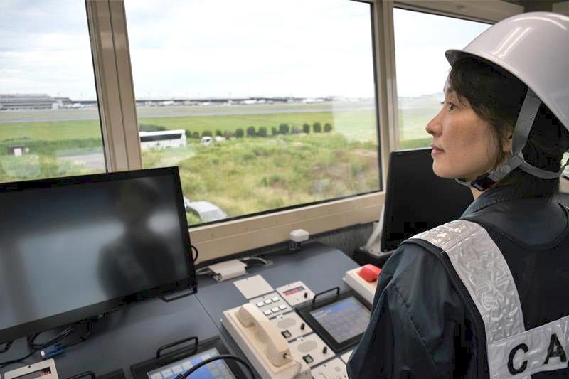 管制卓や電話回線などが備わった非常用管制塔から滑走路を目視する管制官＝成田空港
