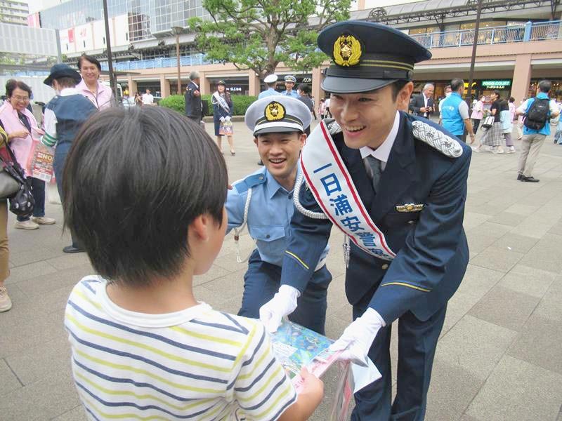 一日署長として交通安全の啓発グッズを渡す泉沢さん（右）＝新浦安駅前
