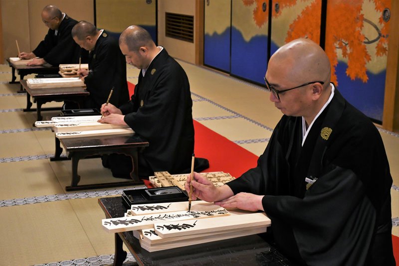 成田山新勝寺で正月準備の護摩札作りが始まり、思いを込めながら筆を入れる僧侶ら＝１５日、成田市