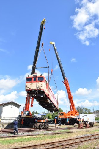 クレーン車２台につり上げられて、前後を１８０度回転するキハ２８＝いすみ市のいすみ鉄道国吉駅
