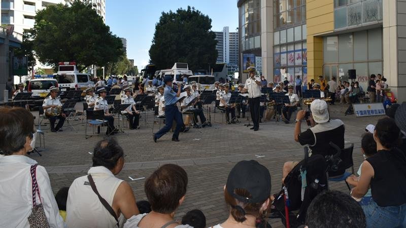 手首に巻いた反射バンドをコミカルにアピールする県警音楽隊＝印西市内のイオンモール千葉ニュータウン
