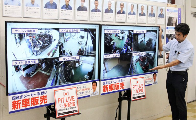 整備工場内の作業をリアルタイムで放映する待合室のモニターと湊原さん＝千葉市稲毛区