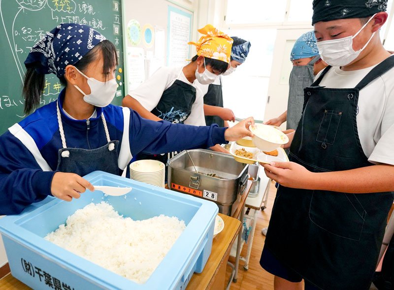 自分たちで田植えをして収穫した新米を給食で配膳する勝浦中２年生＝勝浦市