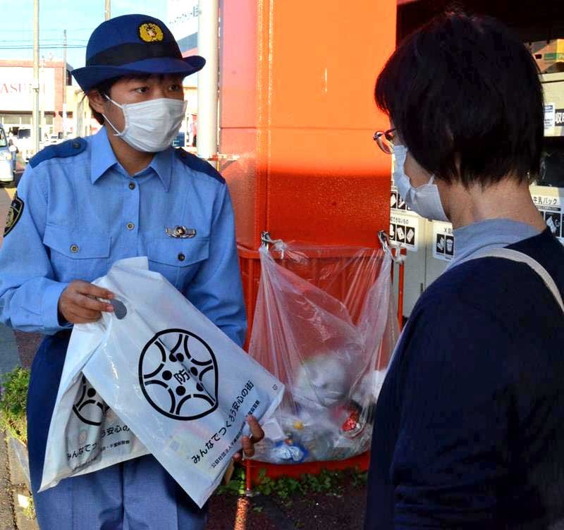 買い物客に自転車の「ツーロック」ができるワイヤー錠が入った袋を配る初任科生（左）＝東金市