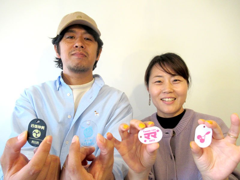 新種の「市川まちガチャ」を出した佐藤宏昭さん（左）と弥生さん。手前左が「行徳神輿」の小判札＝市川市
