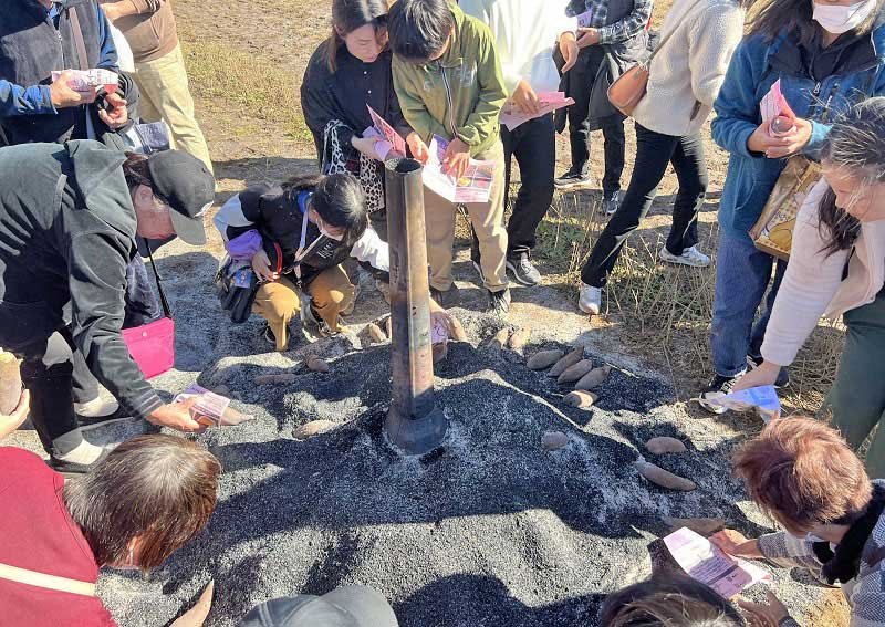 もみ殻でゆっくり焼き上げた焼き芋を手に取る来場者＝１９日、香取市