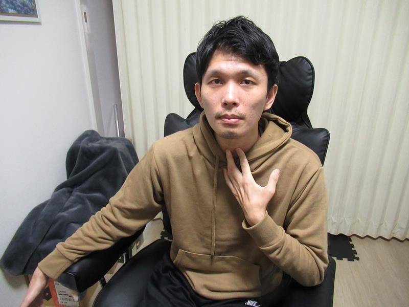 「健康維持に努め。新薬承認を待っている」と語る青木さん。声が裏返ることが増え、のどを押さえて話すことも＝５日、市川市
