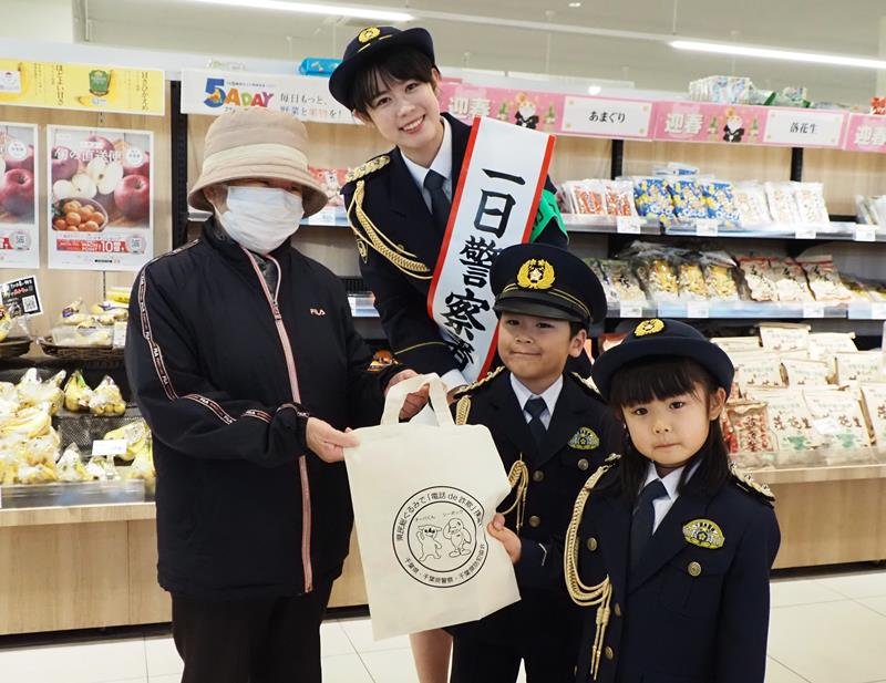 買い物客に防犯を呼びかける一日署長の青山さん（中央）と園児＝君津市
