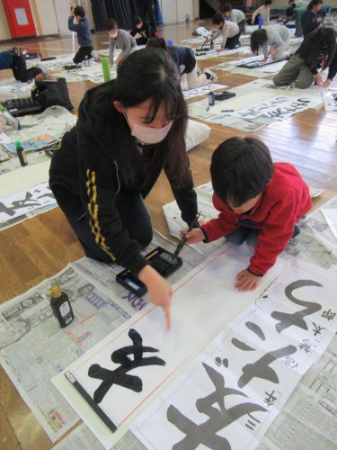 信篤小で行われた「書き初め教室」で、児童にアドバイスする書道部員＝２０日、市川市

