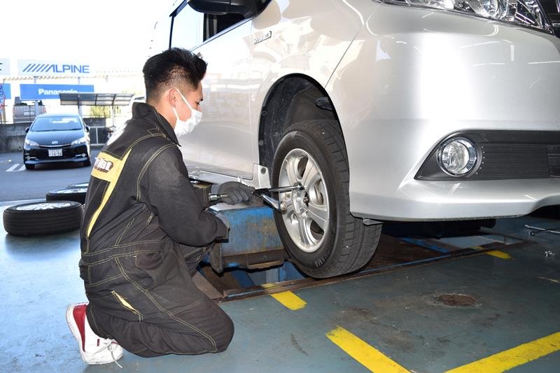 乗用車にスタッドレスタイヤを付ける従業員