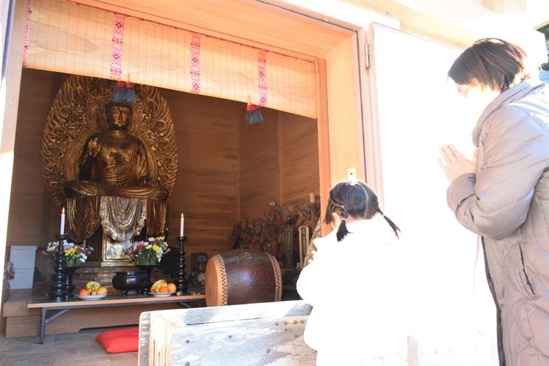 開帳された本尊の木造薬師如来坐像に手を合わせる人たち＝８日、銚子市
