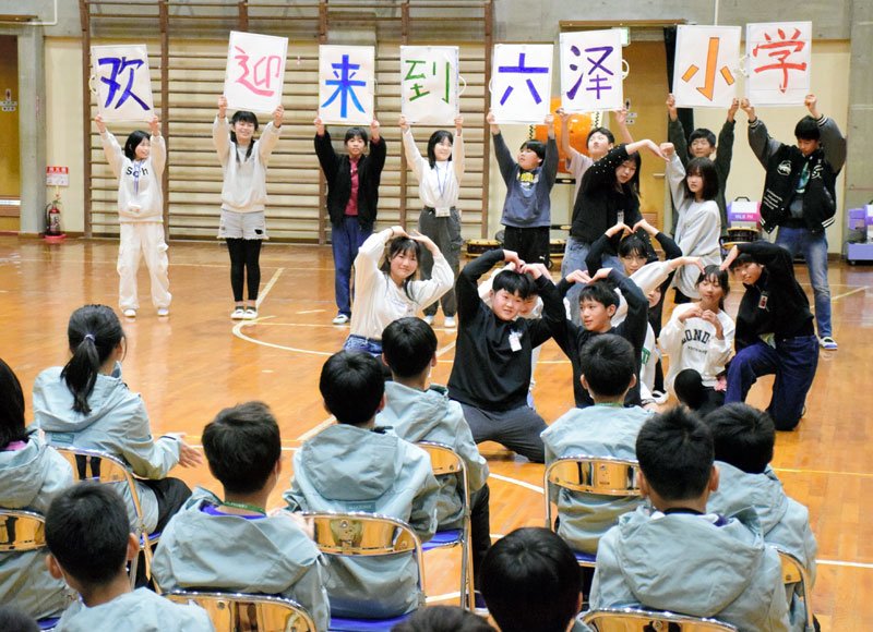 台湾児童（手前）の来校を歓迎するボードを掲げる睦沢小の児童＝１９日、睦沢町
