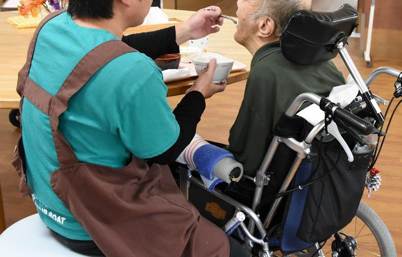 福祉施設利用者の食事の介助をする男性＝千葉県内

