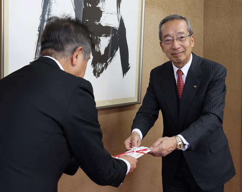 寄付金を手渡す飯沼会長（右）
