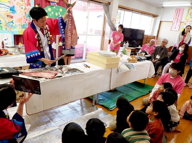 園児の目の前で包丁を振るい、魚をさばいてみせる君津商業高の吉田さん＝君津市