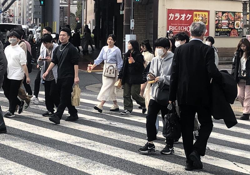 コートを手に持ったり、上着の袖をまくったりして歩く人ら＝２０日午後、千葉市中央区