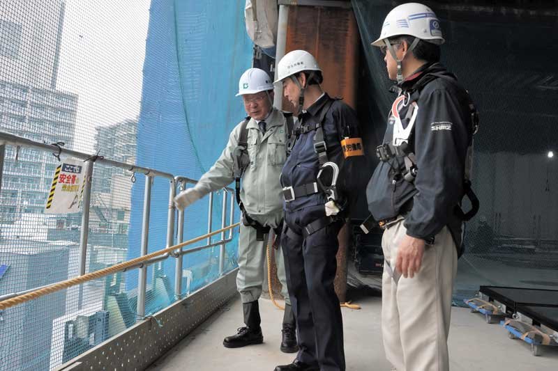 ビル建設現場をパトロールする岩野局長（中央）＝１２日午後、千葉市中央区