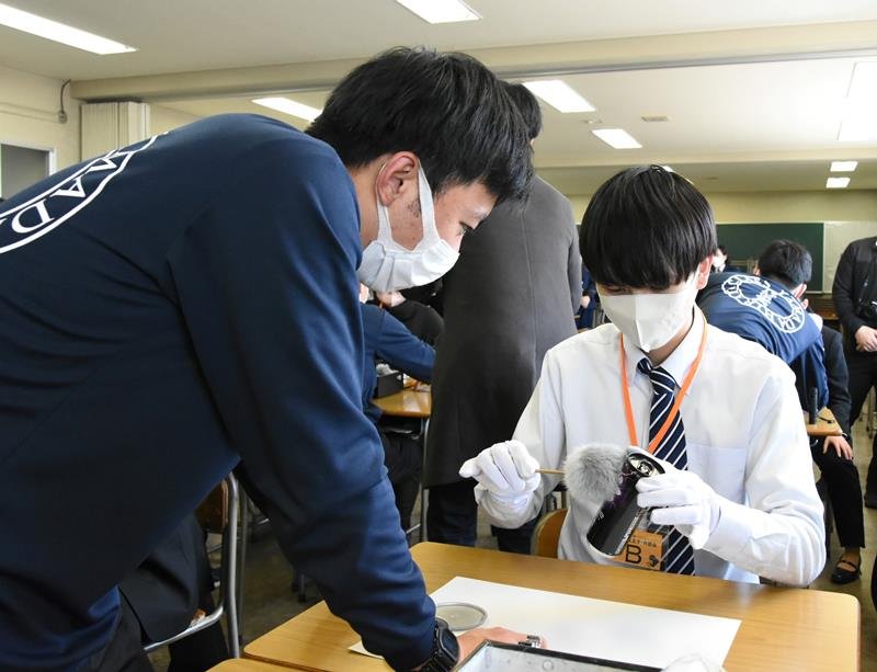 千葉県警が開催したバスツアーで初任科生から指紋の採取方法を教えてもらう参加者（右）＝東金市の警察学校
