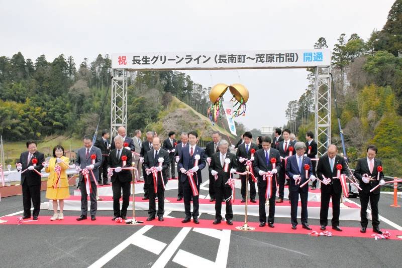 長生グリーンラインの新たな開通区間でテープカットとくす玉割りを行う関係者＝２４日、茂原市
