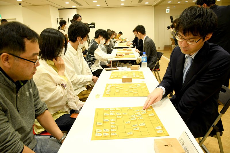名人戦に合わせて開かれた指導対局で訪れた人たちを相手する近藤七段（右）＝２３日、成田市