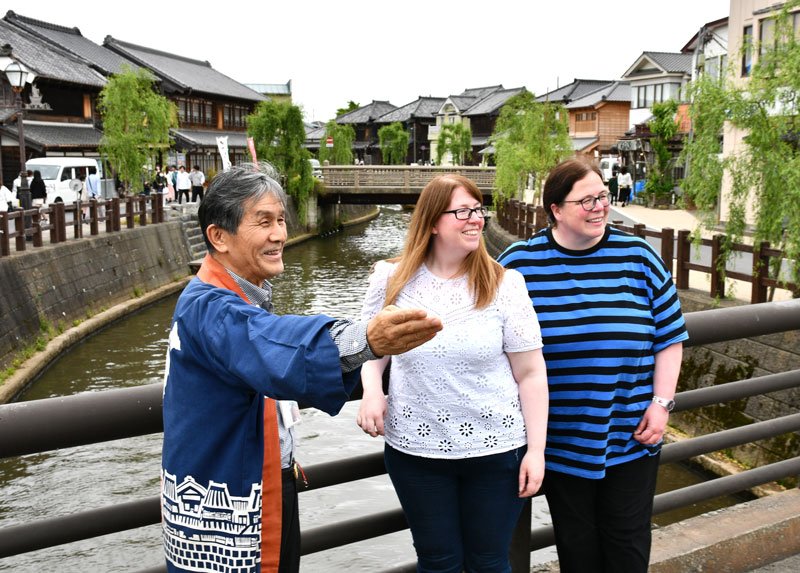 佐原の町並みを訪れた外国人観光客を案内する高谷館長（左）＝香取市