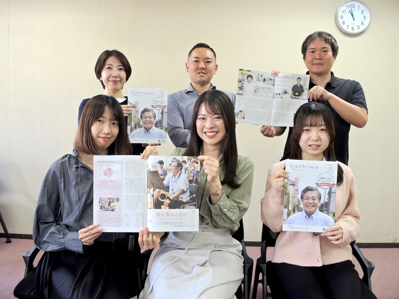 全国広報コンクールに入選した昨年１１月号の「広報かしわ」を手にする柏市の担当職員ら。前列中央が成田さん＝同市