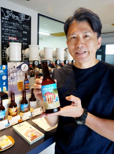 「極東マリブ」の瓶ビールを持つ笠倉代表＝勝浦市
