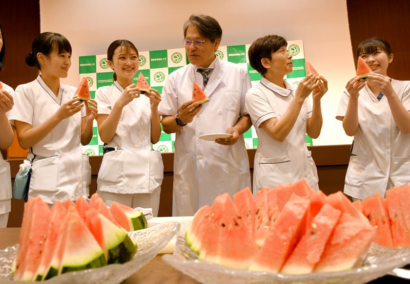 旬を迎えている富里スイカを食べる国際医療福祉大学成田病院の吉野病院長（中央）と看護師ら＝２１日、成田市