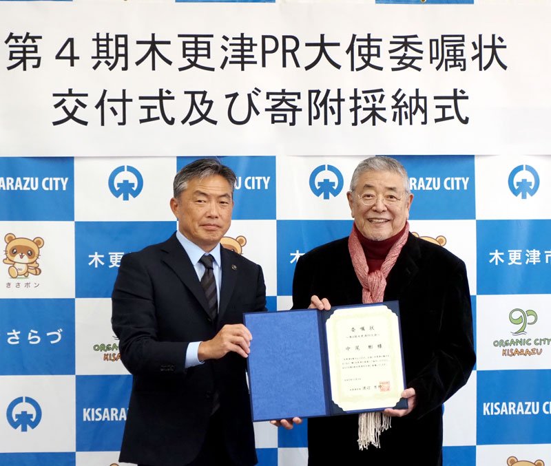 第４期「木更津ＰＲ大使」の委嘱状を手にする中尾彬さん（右）＝昨年１１月、木更津市