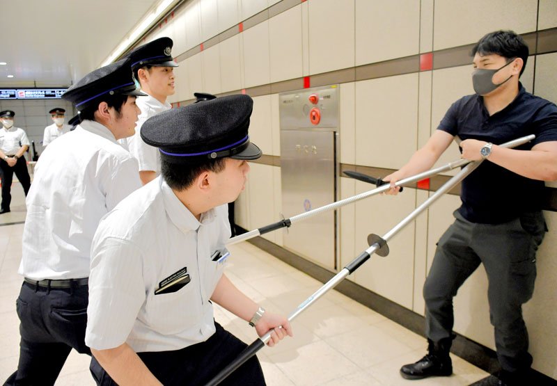 さすまたを使って不審者役の警察官の動きを制止する成田空港駅の駅員ら＝成田市