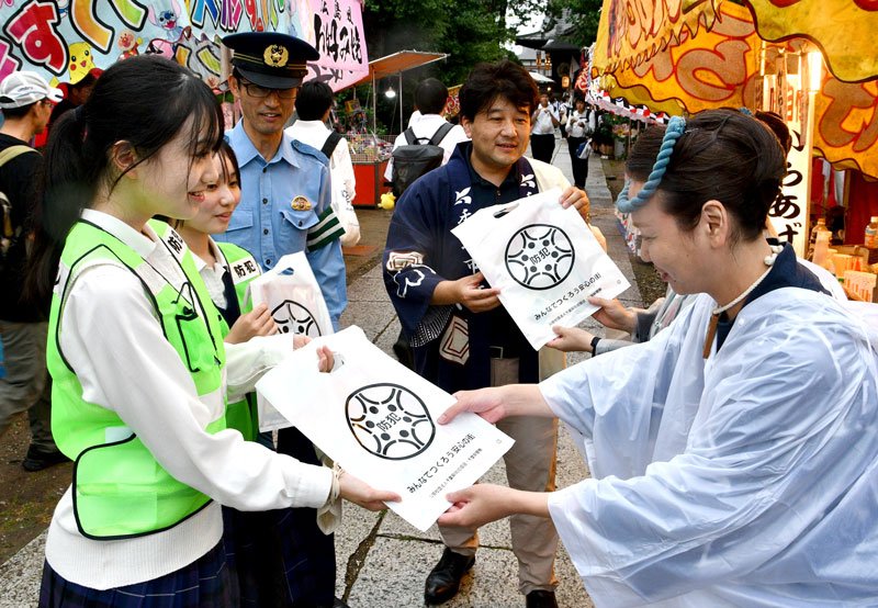 祭り会場を巡回し、啓発物を配る高校生ら＝香取市