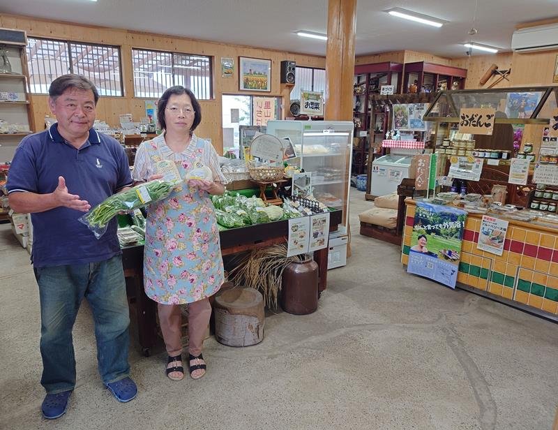 里山ファームの農産物販売所の店内と販売している商品を紹介する山崎さん夫妻＝市原市馬立
