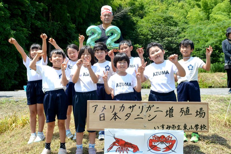 釣り上げたザリガニと記念撮影するいすみ市立東小の１、２年生ら
