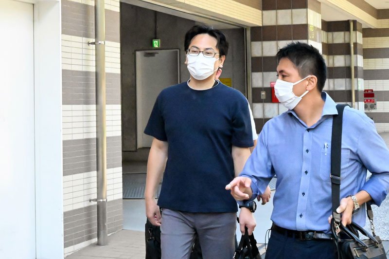 捜査員に任意同行を求められた小坂容疑者（左）＝３０日午前８時２５分ごろ、横浜市鶴見区