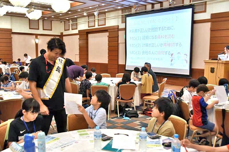 社長役に質問しながら監査報告書を作成する児童＝柏市