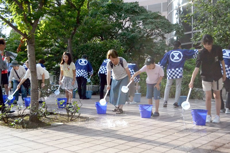 路面に水をまく参加者たち＝３１日、千葉市中央区
