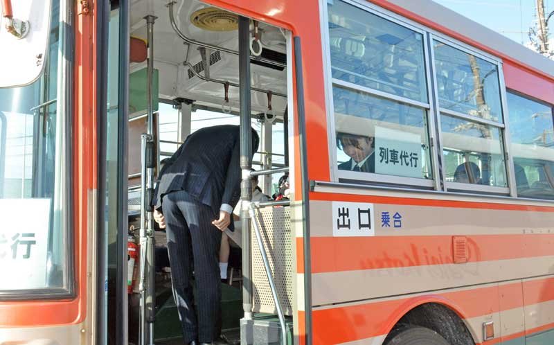 代行バス車内で乗客に頭を下げる、いすみ鉄道の古竹社長＝７日朝、いすみ市