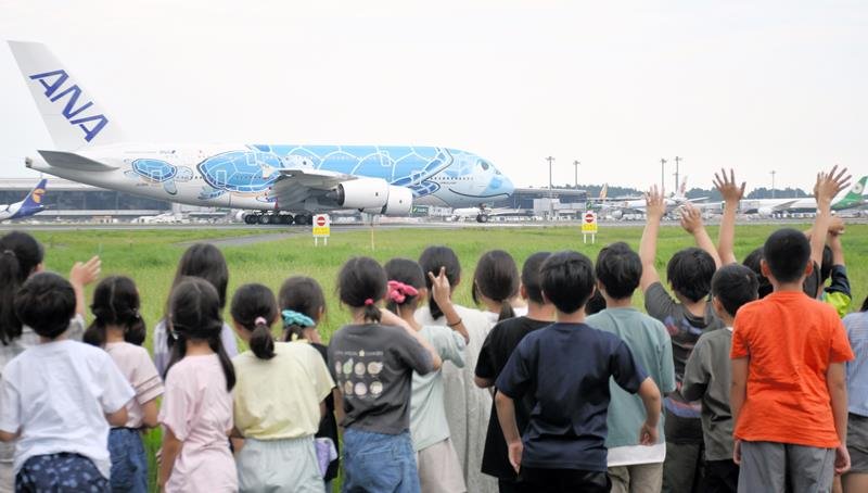 成田空港の滑走路脇で迫力ある着陸シーンを間近で眺める児童＝成田市
