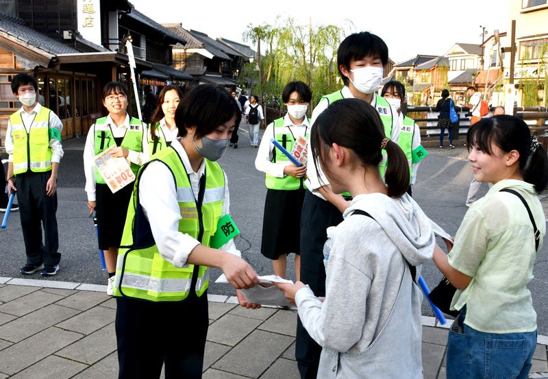 佐原の大祭の会場で啓発物を配る高校生＝１１日、香取市