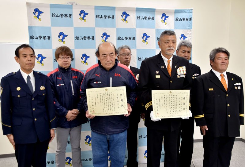 感謝状を掲げる山岸さん（前列左から２人目）と館山市消防団の吉野団長（同３人目）＝８日、館山署